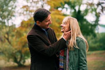Mature couple showing affection during a walk in the park surrounded by autumn colors