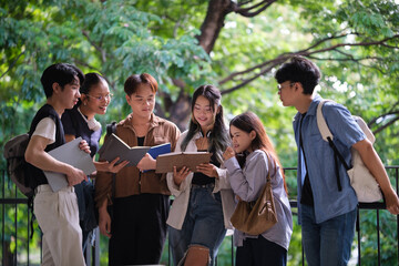 Group of college students standing together, reading books and sharing ideas in a green outdoor setting.