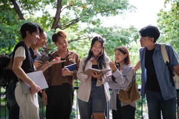 Cheerful group of university students reading a book and discussing ideas together in a natural campus setting.