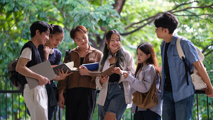 Happy group of university students studying together in a leafy outdoor setting.