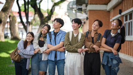 Cheerful university students stand arm-in-arm enjoying friendship and good times on campus.