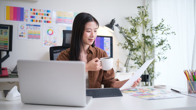Creative woman enjoying coffee while analyzing color charts in a bright and stylish home office.
