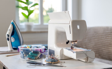 Sewing Machine, Iron, And Sewing Supplies On The Table At Home