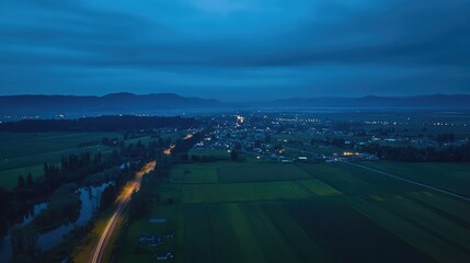 Fototapeta premium Rural town lights illuminating twilight agricultural landscape