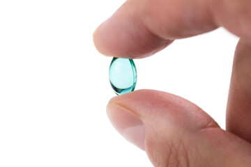 Man's hand holding blue gel capsule isolated on white background. Close up. High resolution product
