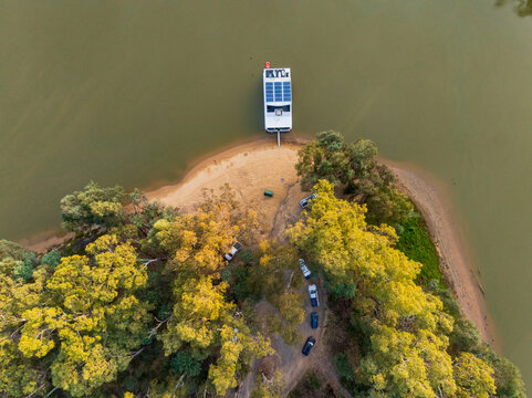 Aerial view of 4wds and a houseboat on the sandy shores of an inland river at Moama, New South Wales
