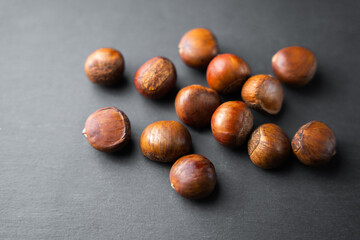 Raw chestnuts scattered on dark background, organic autumn nuts with natural brown shells, healthy seasonal food rich in nutrition, perfect ingredient for cooking, roasting,