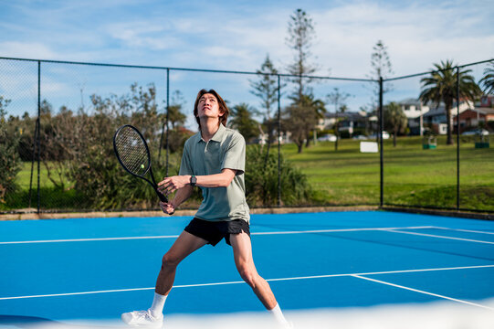A young man focuses on hitting a tennis ball while practicing