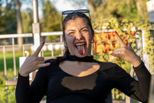 Young woman expressing rebellious attitude with a rock and roll hand sign and sticking out tongue
