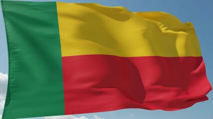Waving flag of Benin, a West African nation, under a clear blue sky, symbolizing national pride and independence on a bright sunny day with the colors green, yellow, and red prominently displayed