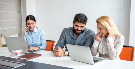Businessman and businesswoman working on laptop discussing good news received by email