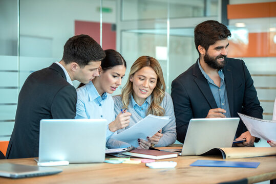 Corporate colleagues examining project documents and reviewing digital reports together