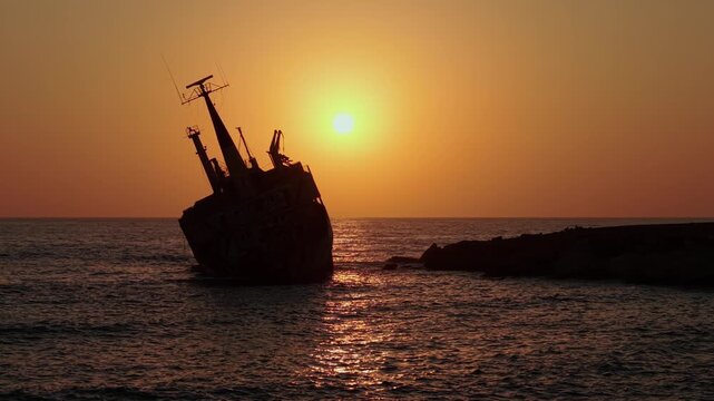Tourism concept. Cyprus - a tourist destination. Mediterranean Sea and the abandoned ship EDRO III at amazing sunset time. EDRO III resting off the rocks near the Sea Caves northwest of Paphos, Cyprus