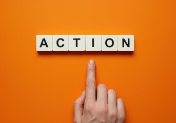 A hand pointing upwards towards letter tiles spelling ACTION on an orange background