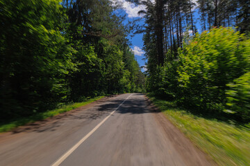 The effect of speed on the road and blurred objects. View of the road on a sunny summer day.