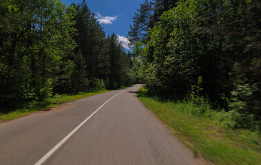 The effect of speed on the road and blurred objects. View of the road on a sunny summer day.