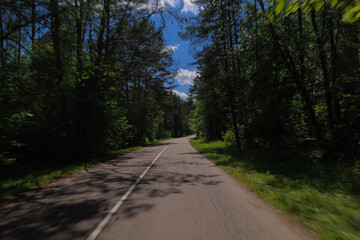 Fototapeta premium The effect of speed on the road and blurred objects. View of the road on a sunny summer day.