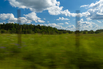 The effect of speed on the road and blurred objects. Roadside view, road and landscape, forest and field.