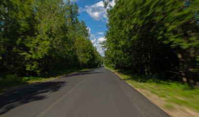 The effect of speed on the road and blurred objects. View of the road on a sunny summer day.