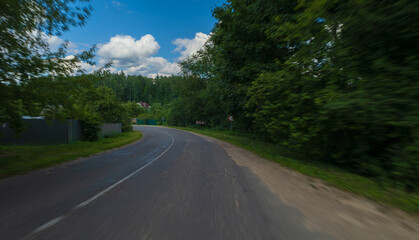 The effect of speed on the road and blurred objects. View of the road on a sunny summer day.