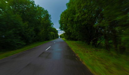 Obraz premium Road in the countryside, roadside and asphalt, green forest and fields, blue sky and clouds 
