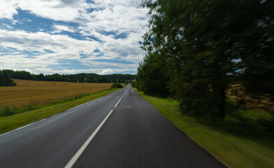 The effect of speed on the road and blurred objects. View of the road on a sunny summer day.