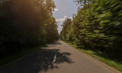 Fototapeta premium The effect of speed on the road and blurred objects. View of the road on a sunny summer day.