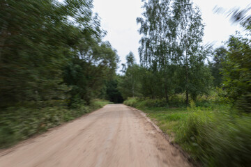 The effect of speed on the road and blurred objects. View of the road on a sunny summer day.