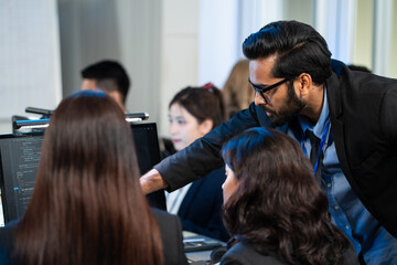 Diverse software engineer team analyzing and debugging code on a computer monitor in a modern tech office, reviewing complex data and programming, work in cybersecurity, system maintenance