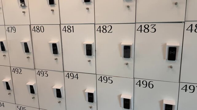Rows of white modern lockers with electronic combination locks for storing personal belongings in a public place, such as an office, school, or fitness center, providing secure storage