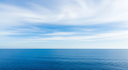 Fototapeta premium Calm blue ocean meets a light blue sky with cirrus clouds along the horizon on a bright sunny day.