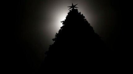 Low angle silhouette Christmas tree against a bright light source, viewed from below, dramatic