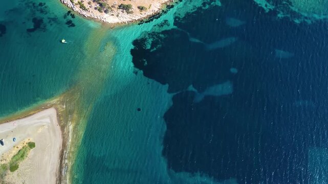 aerial perspective showcasing the stunning turquoise waters meeting a rugged coastline, with a small sandy beach and a rocky outcrop, captured on the way to the ancient city of Knidos in Turkey. This 
