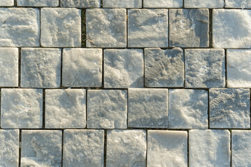 Square stone tiles with rough, natural texture arranged in a grid pattern, showing subtle color variations. Suitable for backgrounds, architectural design, flooring, and construction context.