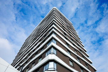 A modern high-rise building with a brown and white façade, large windows, and geometric lines. Contemporary style, minimalism, functionality, and harmony with the urban environment.