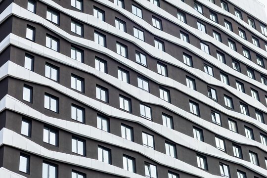 A modern residential complex with a wave-shaped façade, finished in dark tones with white accents. The architecture emphasizes dynamism and style, creating a unique appearance.