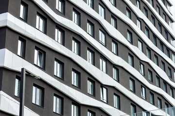 The building's fa&ccedil;ade is graphite-colored and features a wave-like design. White horizontal elements create a sense of movement, and the evenly spaced windows emphasize the contemporary style.