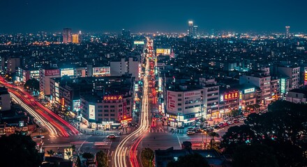 Obraz premium A vibrant, high-angle view of a bustling Asian city at night. Long-exposure light trails from traffic and glowing neon signs create a dynamic and energetic urban scene.