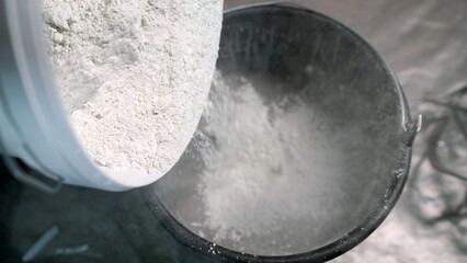 Pouring white plaster powder into a black bucket