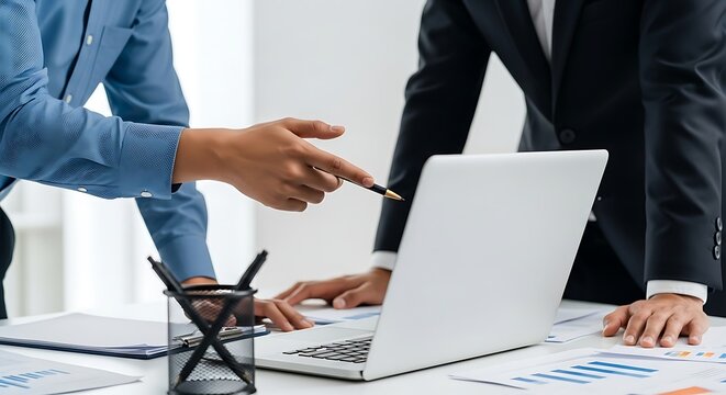Business colleagues discussing data and strategy on a laptop in the office
