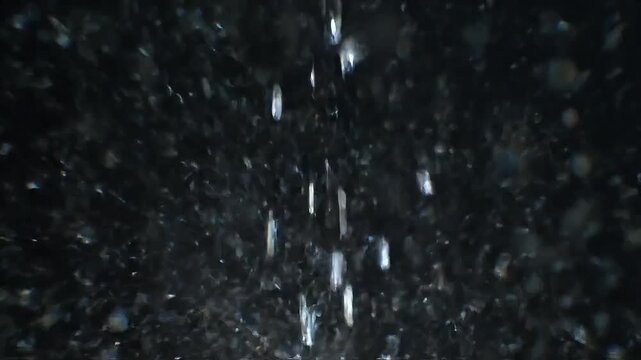 Abstract falling water droplets against a dark background, creating a mesmerizing, dynamic effect.