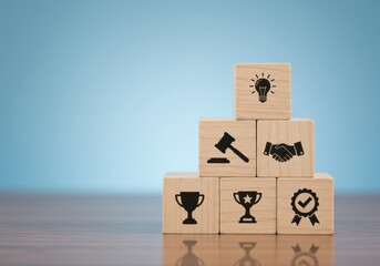 A pyramid of wooden blocks with icons symbolizing achievement and success on a reflective surface against a blue background