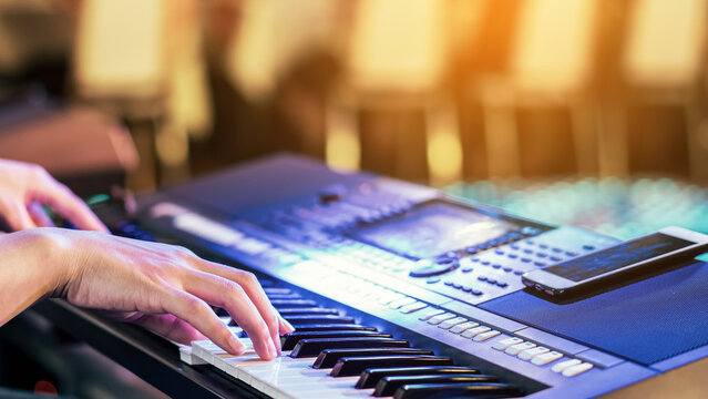 Hands of male musician press digital electronic keyboard synthesizers on concert stage. Pianist man hands play the keys of electronic piano. Piano music pianist hand playing. Selective focus on hand.