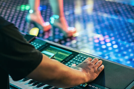Hands of male musician press digital electronic keyboard synthesizers on concert stage. Pianist man hands play the keys of electronic piano. Piano music pianist hand playing. Selective focus on hand.