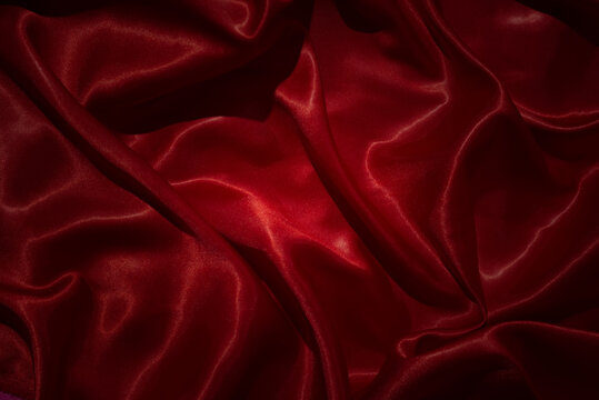 Top view  shiny red silk fabric with smooth, flowing folds and light reflections.