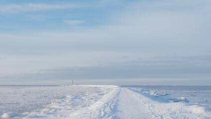 Snowy Path to Lighthouse on Frozen Seashore in Winter