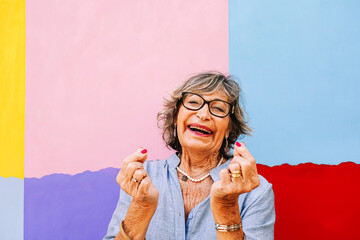 Senior woman expressing joy, laughing at colorful background