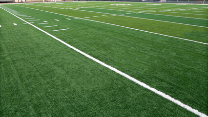 American football field, showcasing meticulously maintained green grass surface, marked with white yard lines and numbers