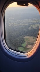Aerial view of patchwork fields and forests seen through an airplane window at sunset