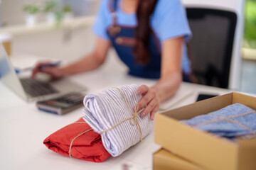 Asian adult woman entrepreneur packaging apparel products processing customer orders shipping online retail small business home office